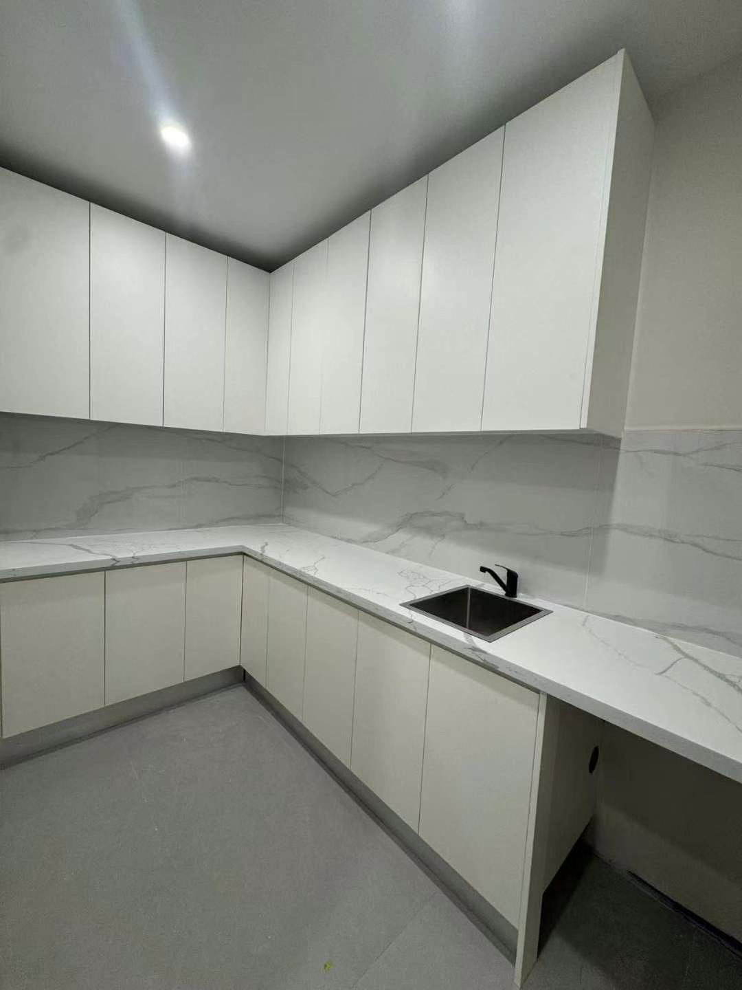 Compact kitchen with light cabinetry and stone-look surfaces