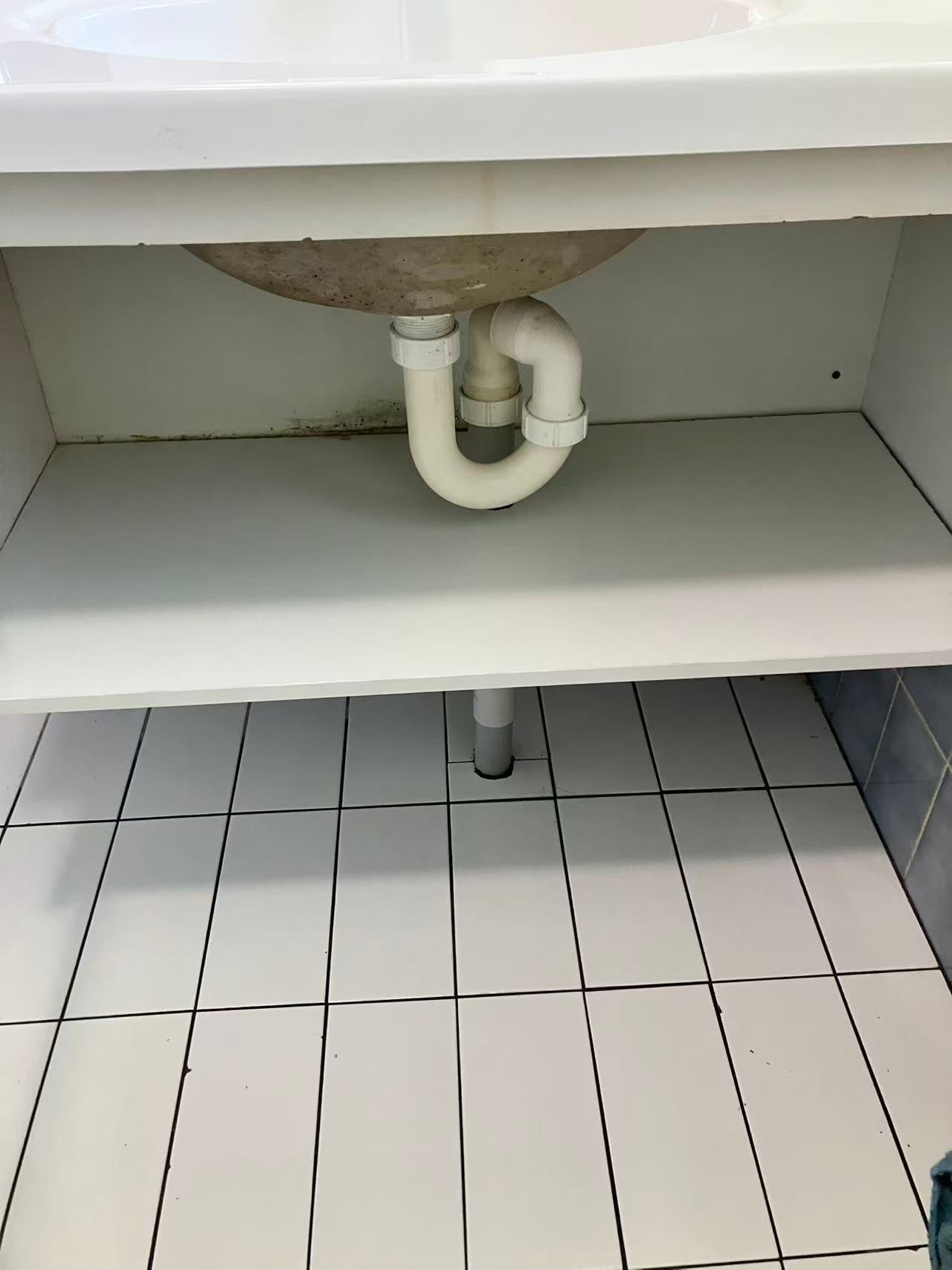 Bathroom vanity plumbing and storage detail