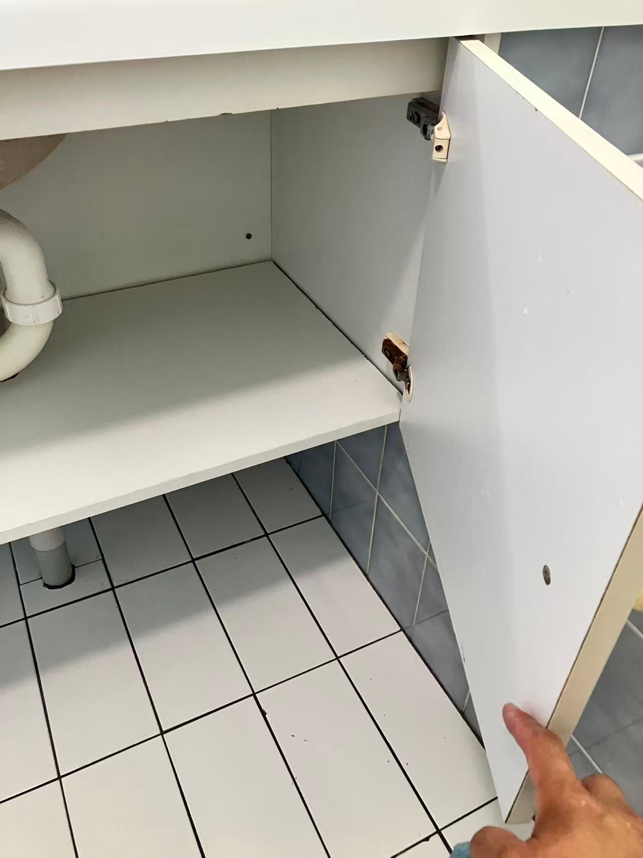 Open vanity cupboard showing plumbing access